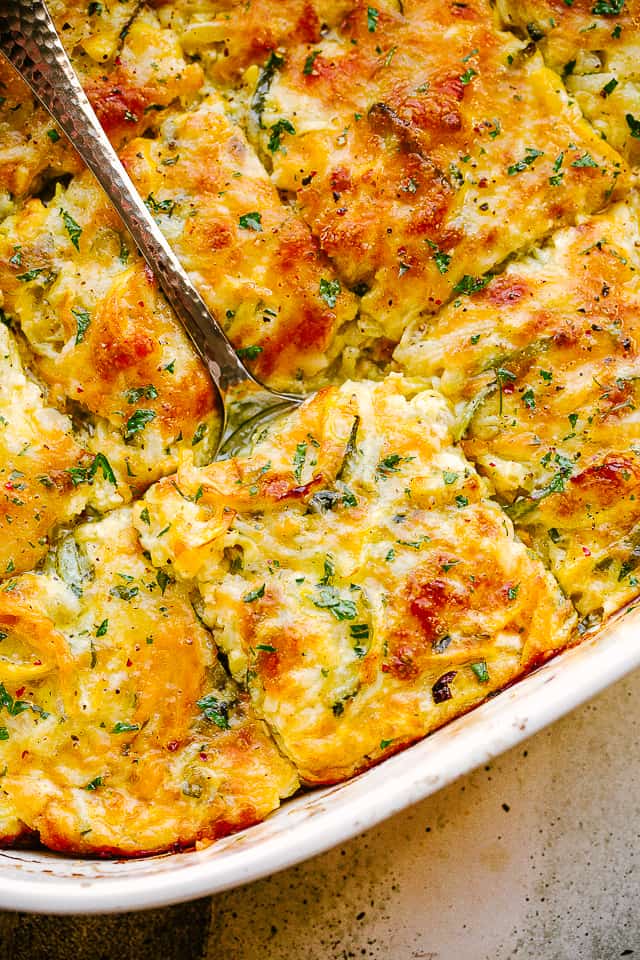 scooping out zucchini squash casserole from baking dish