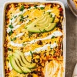 Enchilada casserole in a pan, with a corner piece missing to reveal the food's texture.