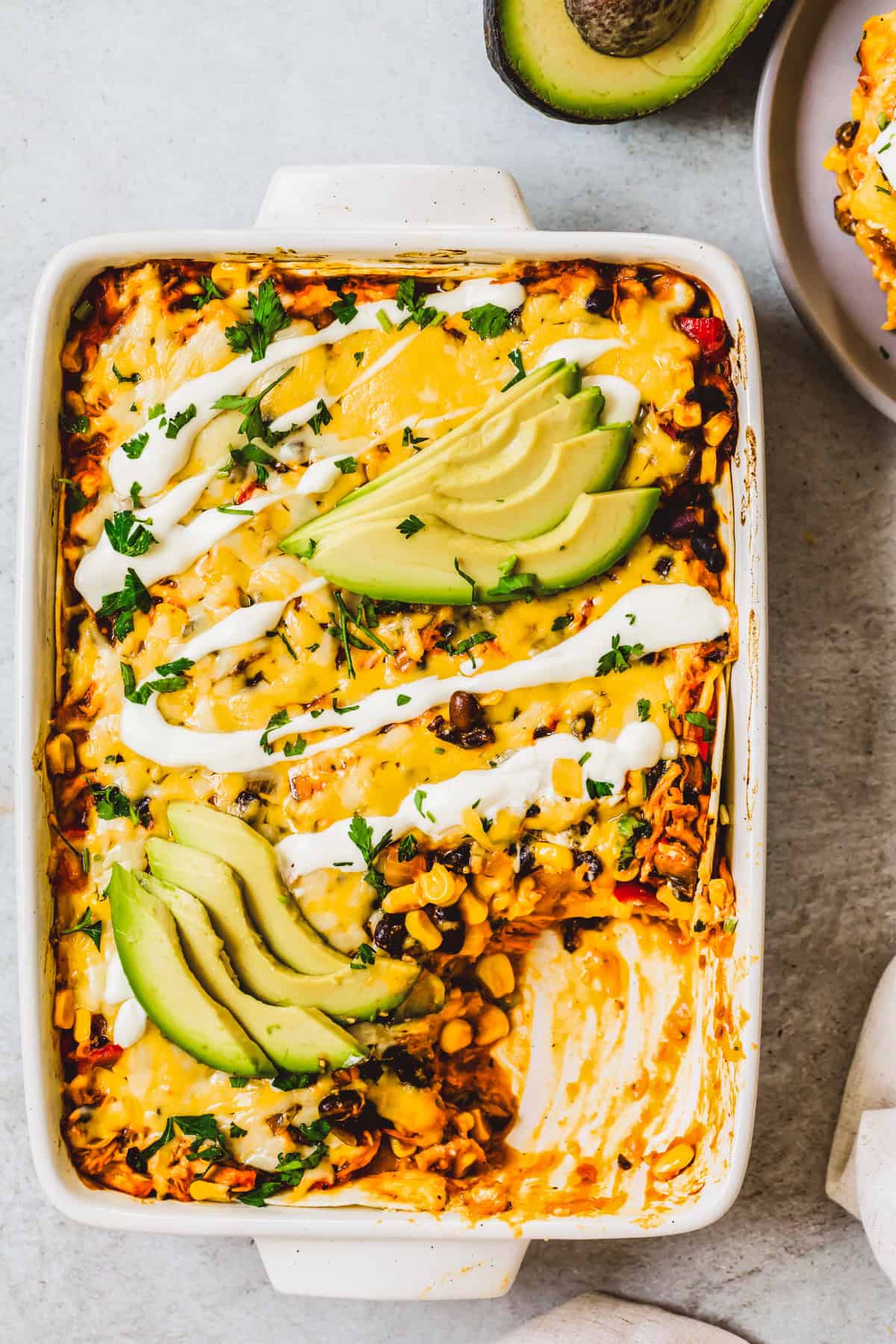 Enchilada casserole in a pan, with a corner piece missing to reveal the food's texture.