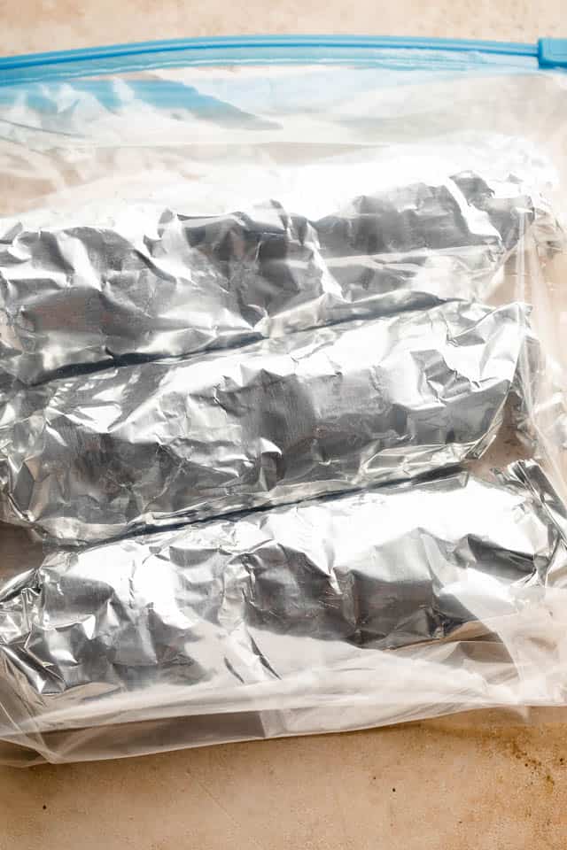 individual burritos wrapped in foil and placed inside ziploc bags.