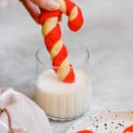 A Candy Cane Cookie Being Dipped into a Cold Glass of Milk