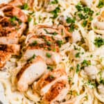 A Close-Up Shot of Sliced Chicken Breasts and Fettuccine Pasta with Alfredo Sauce