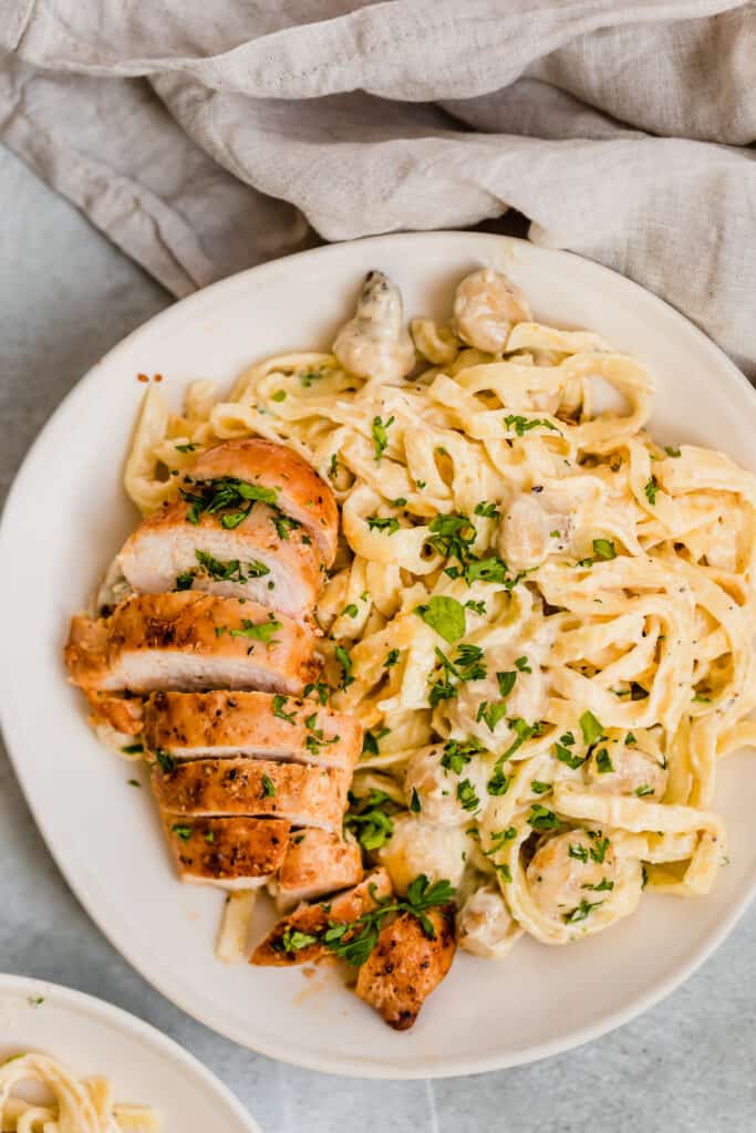 A Bowl of Creamy Fettuccine Alfredo with Mushrooms and Sliced Chicken Breast