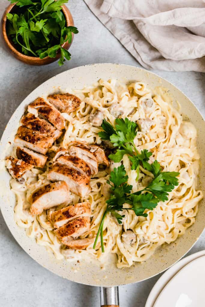 Two Sliced Chicken Breasts Over a Bowl of Creamy Fettuccine Alfredo