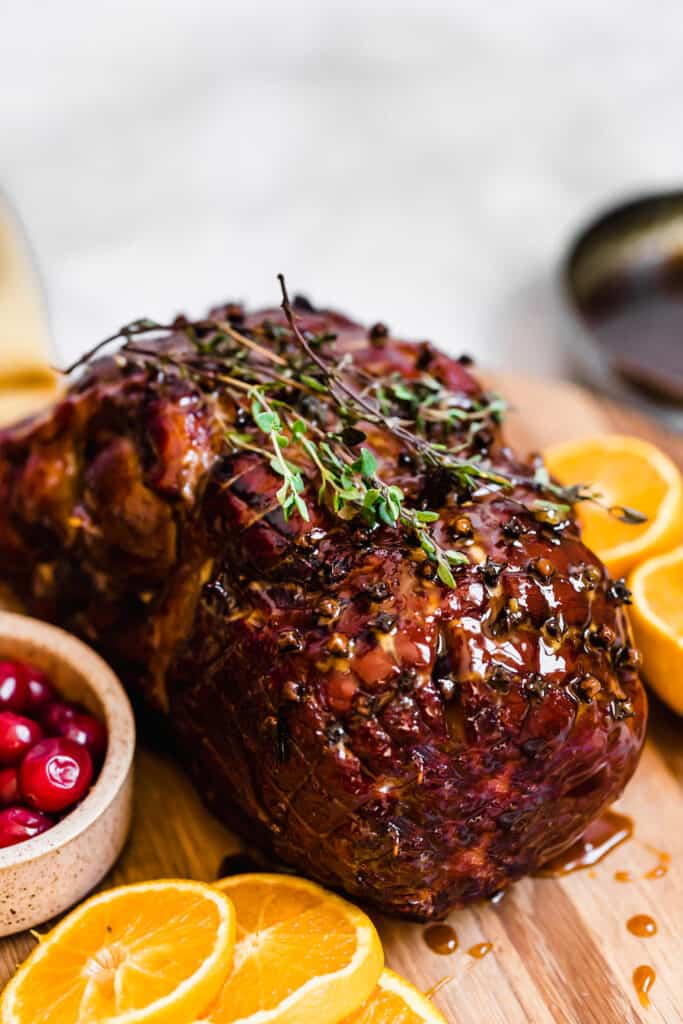 A Christmas Ham on a Wooden Surface with Fruits Surrounding It