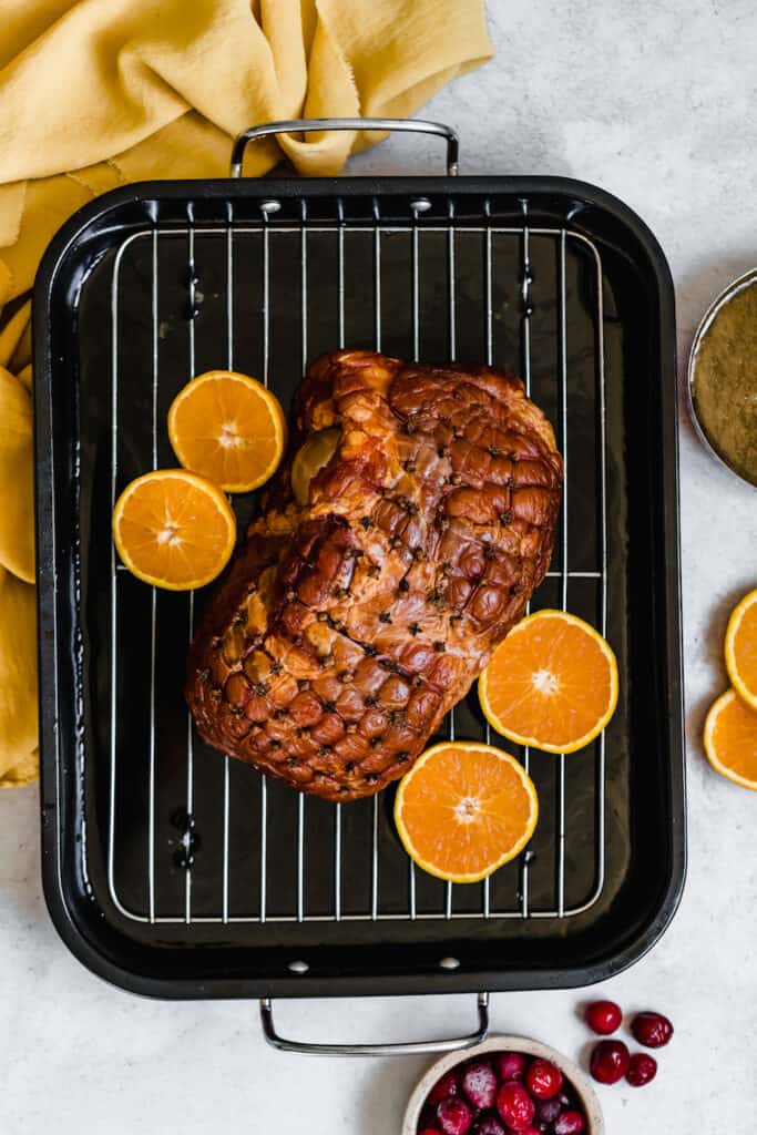 A Christmas Ham on a Roasting Pan with Four Orange Slices