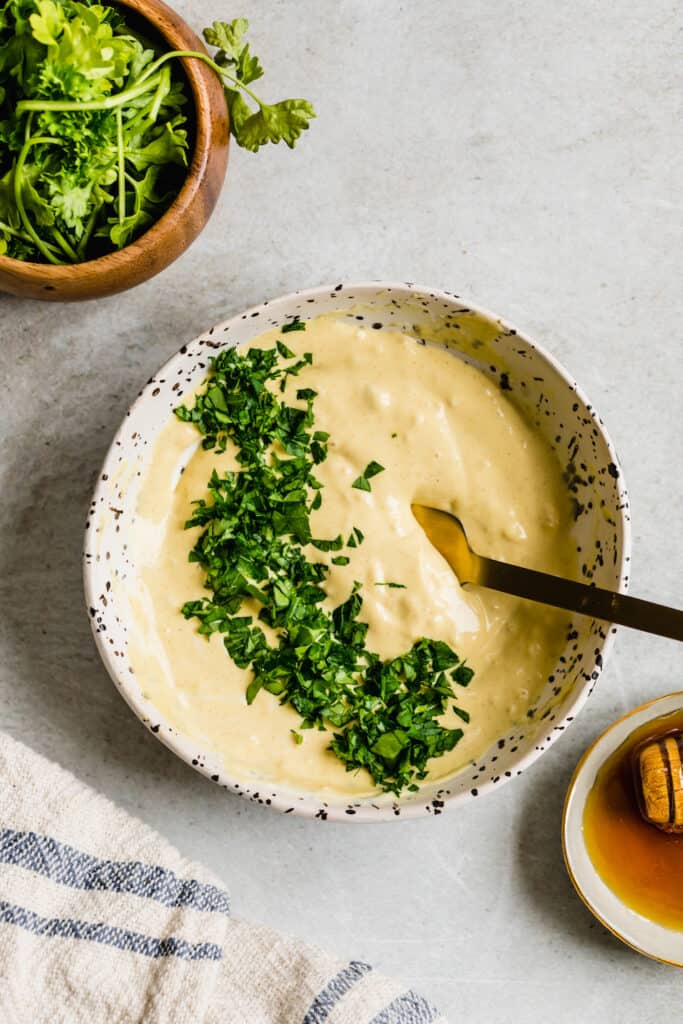 A Bowl of Mayonnaise with Chopped Parsley In It