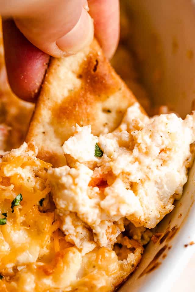 dipping into hot crab dip with pita chip