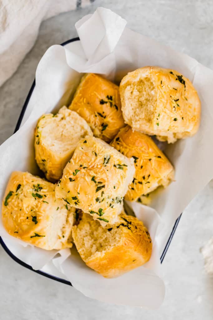 Seven Soft Parmesan Dinner Rolls in a Basket Lined with Tissue Paper