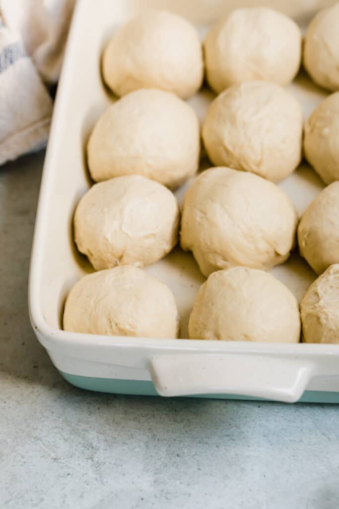 Balls of Dinner Roll Dough Lined Up in a Baking Pan