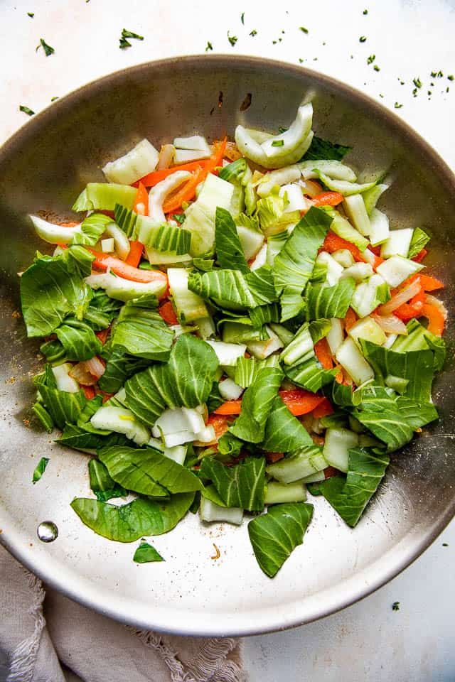 stir frying bok choy, onions, and bell peppers in a skillet