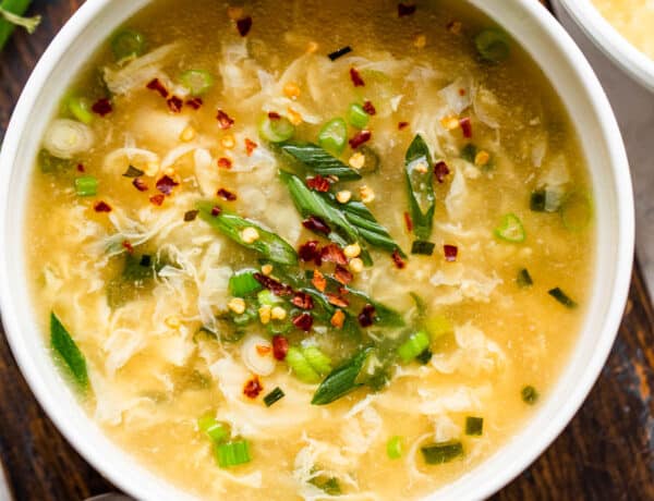overhead shot of a bowl with eggdrop soup garnished with green onions and red pepper flakes