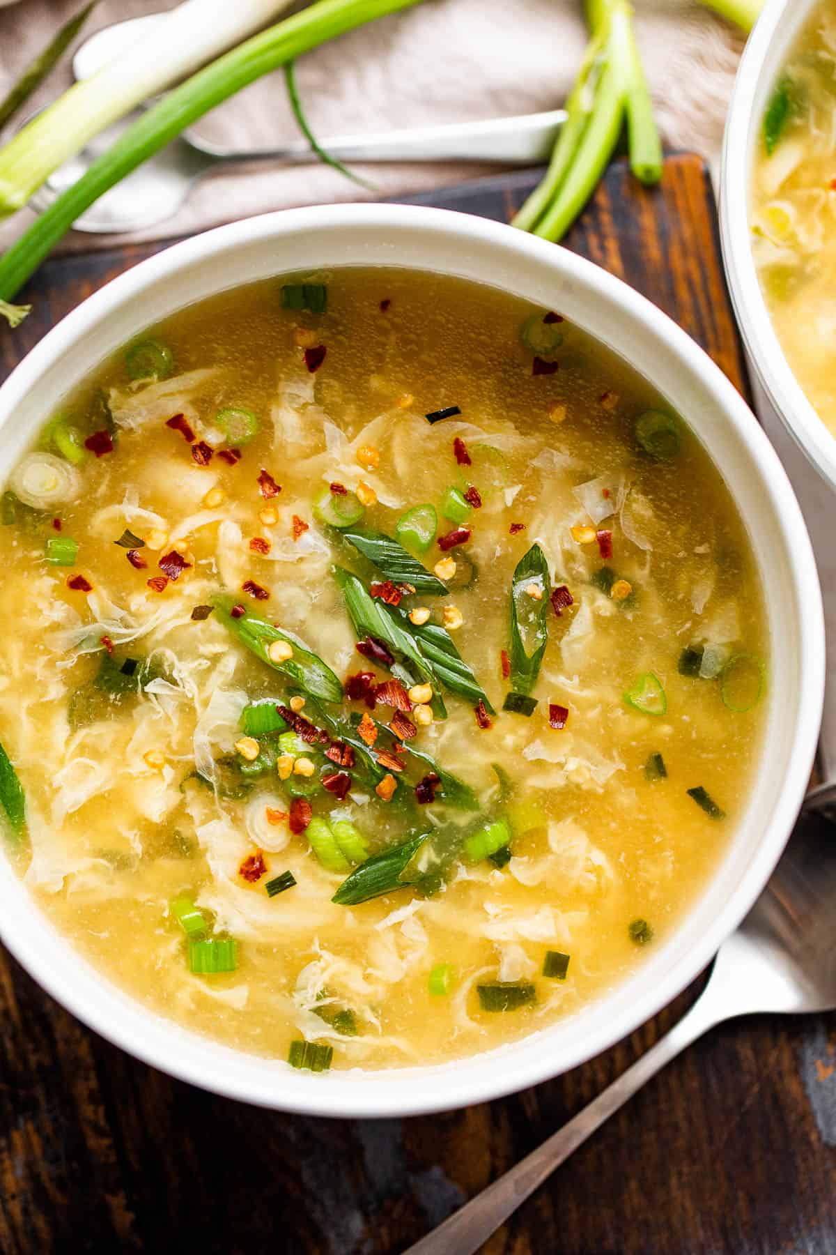 overhead shot of a bowl with eggdrop soup garnished with green onions and red pepper flakes