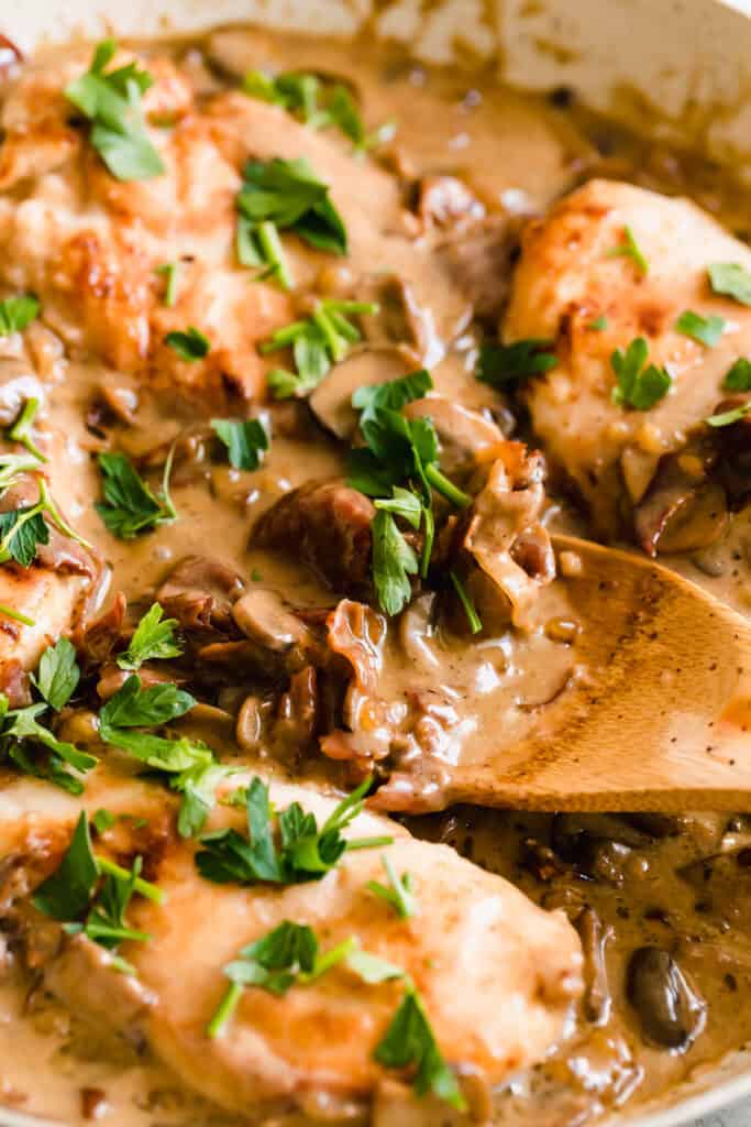 Close up of mushrooms cooking in a creamy marsala sauce with fresh herbs sprinkled on top.