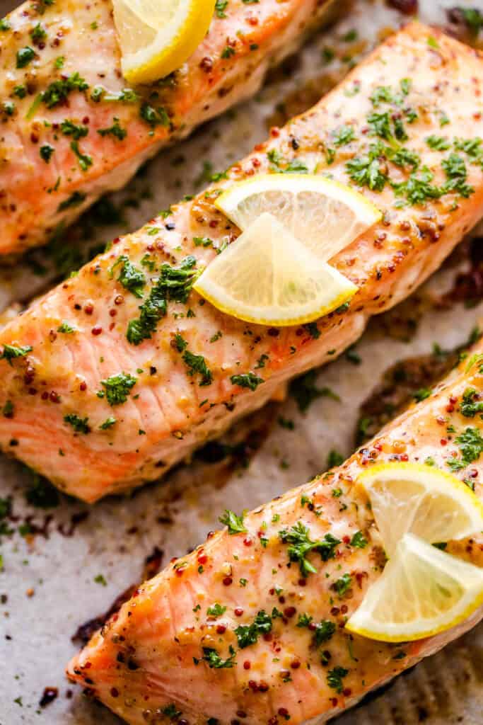 up close photo of maple mustard salmon fillets garnished with parsley and lemon slices