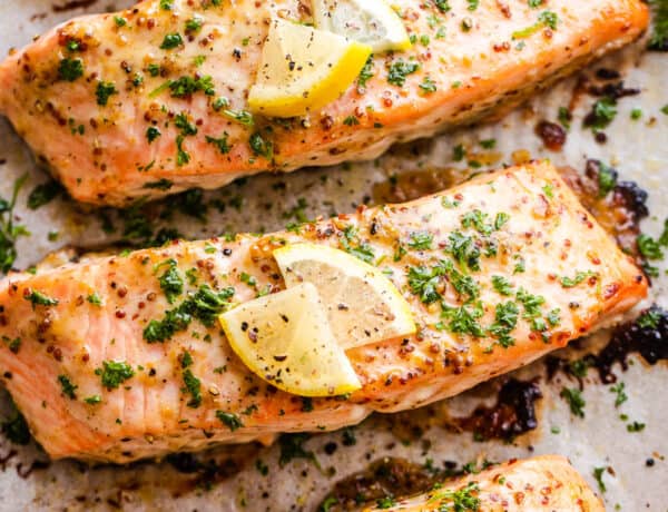 four baked maple mustard salmon fillets on a baking sheet