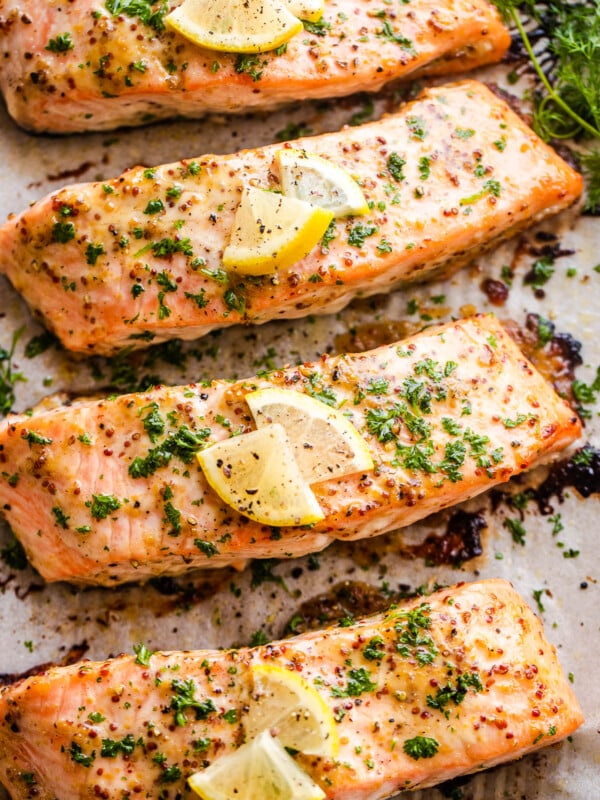 four baked maple mustard salmon fillets on a baking sheet