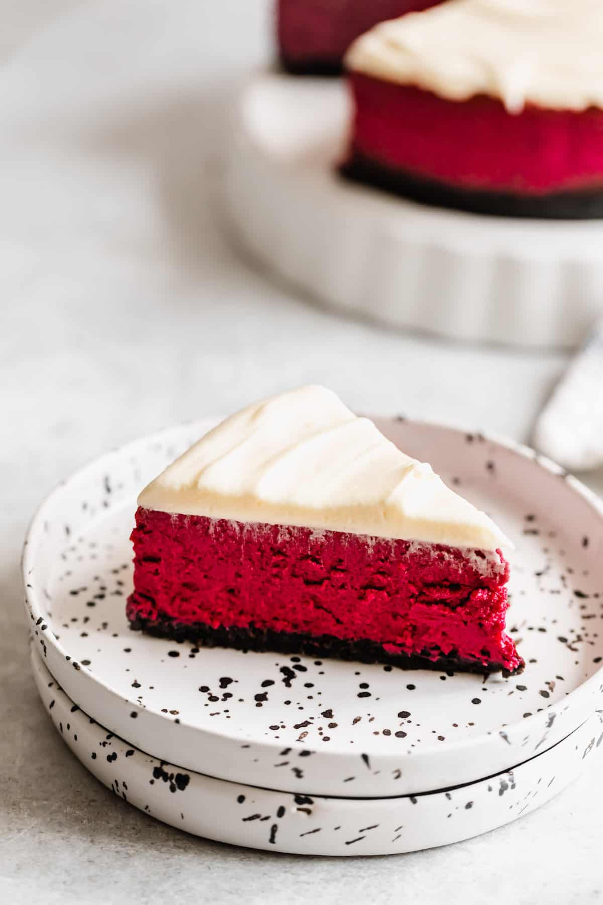 A Piece of Red Velvet Cheesecake on a Black and White Speckled Plate