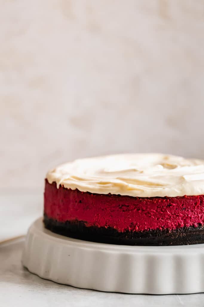 A Vibrant Red Velvet Cheesecake on a Cake Stand with a White Background