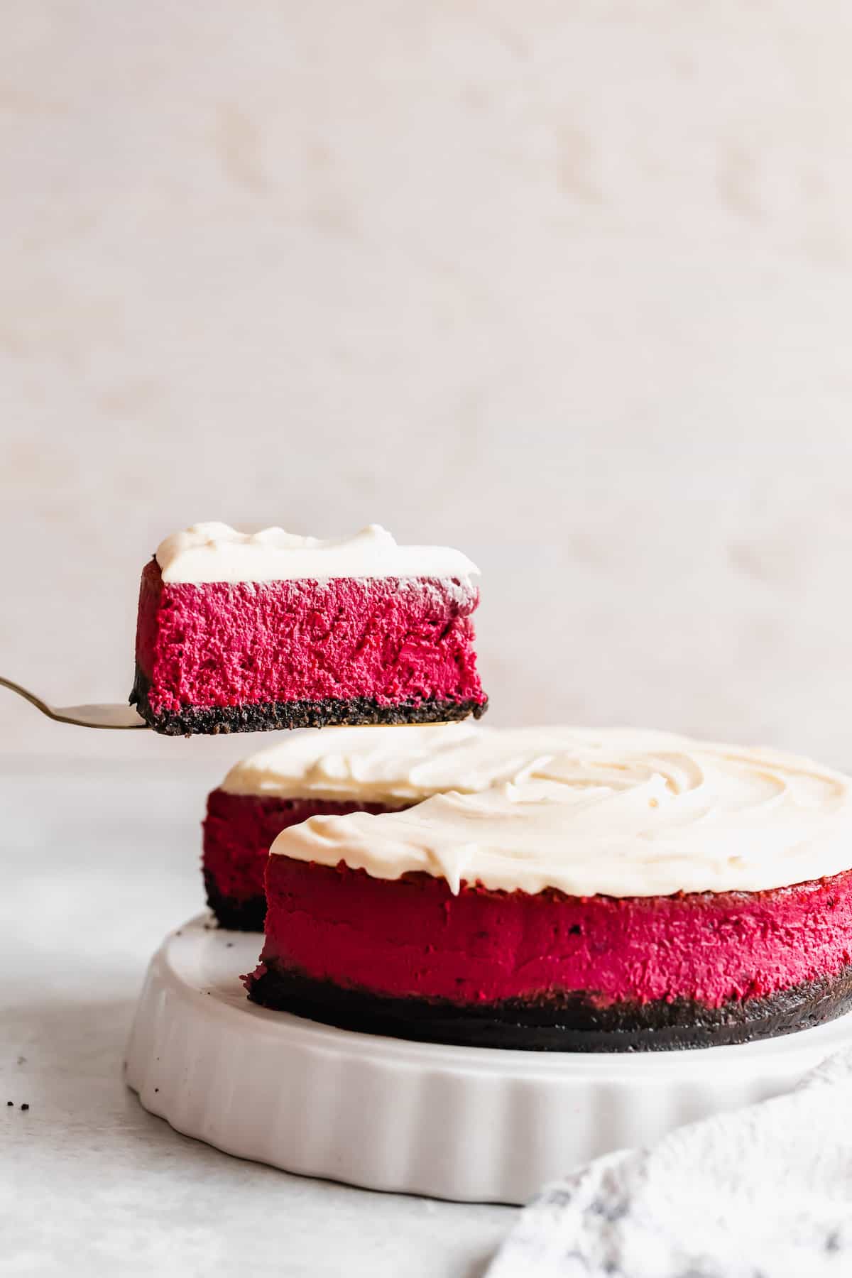 A Slice of Red Velvet Cheesecake Being Lifted From the Rest of the Cake with a Spatula