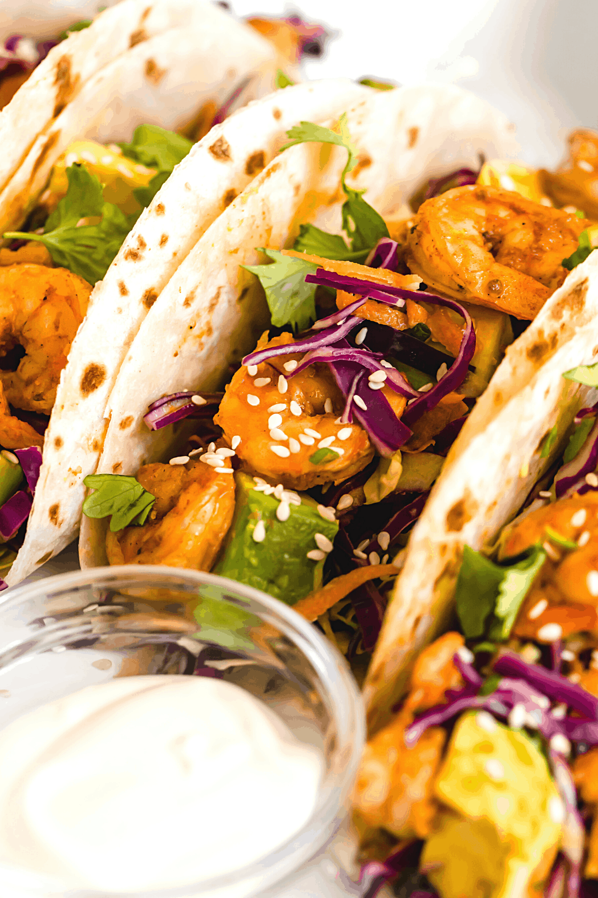 A Platter Holding Four Shrimp Tacos and a Dish of Dressing