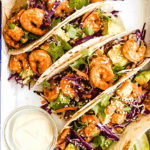 Four Shrimp Tacos Topped with Asian Slaw on a Serving Platter