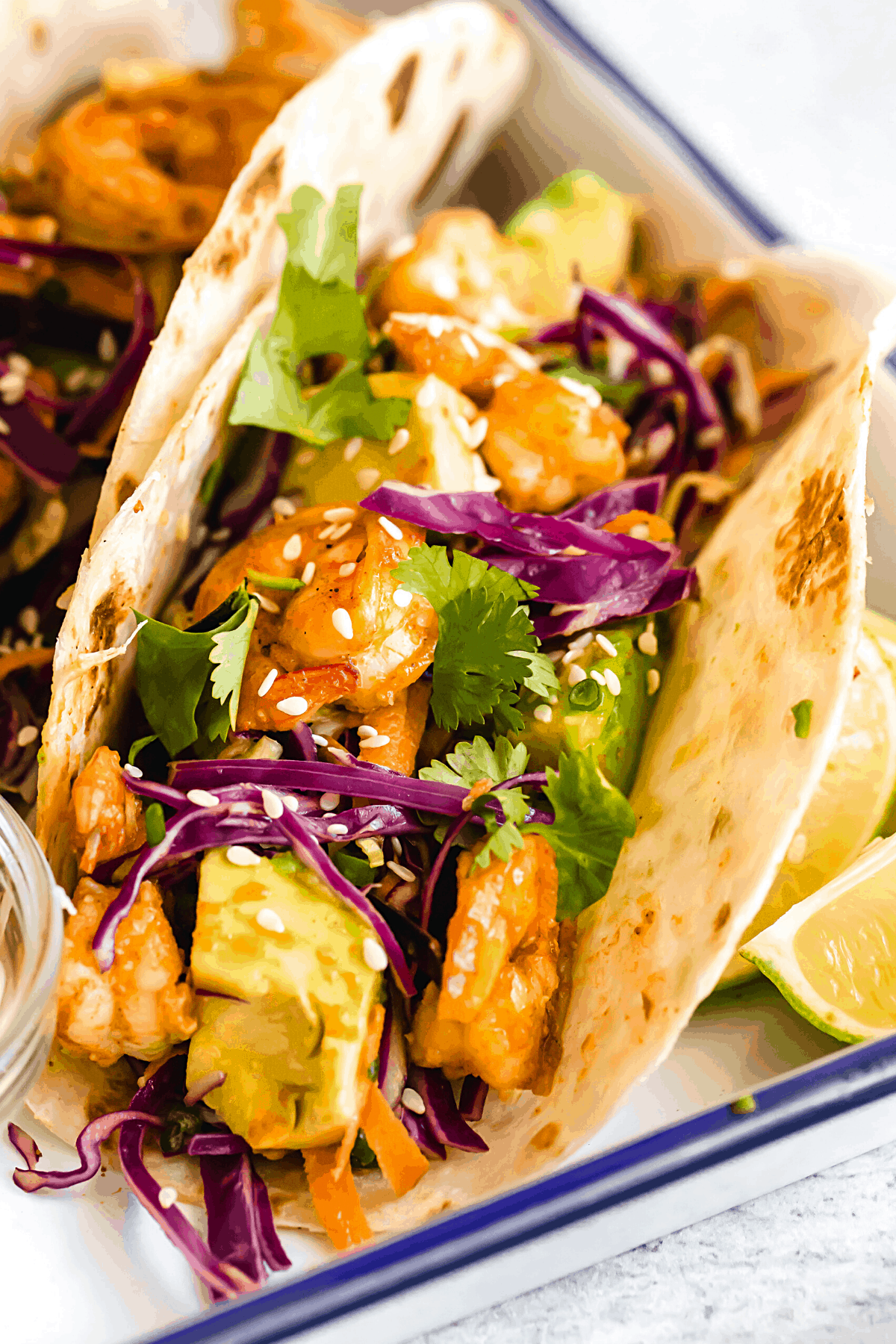 A Platter Holding Four Shrimp Tacos and a Dish of Dressing