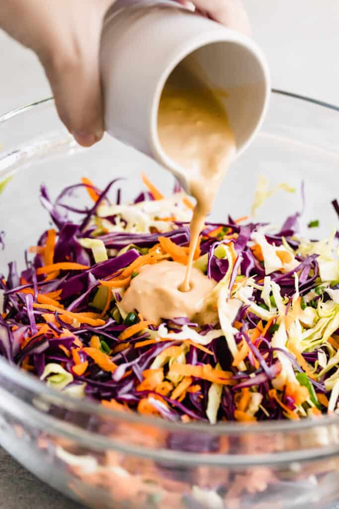 Asian Dressing Being Poured Over the Cabbage Slaw Mixture
