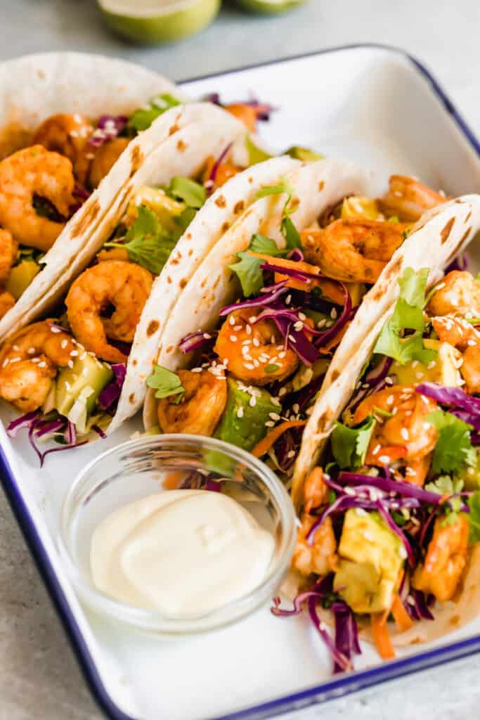 A Platter Holding Four Shrimp Tacos and a Dish of Dressing