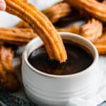 A Homemade Churro Being Dipped Into a Dish of Chocolate Sauce