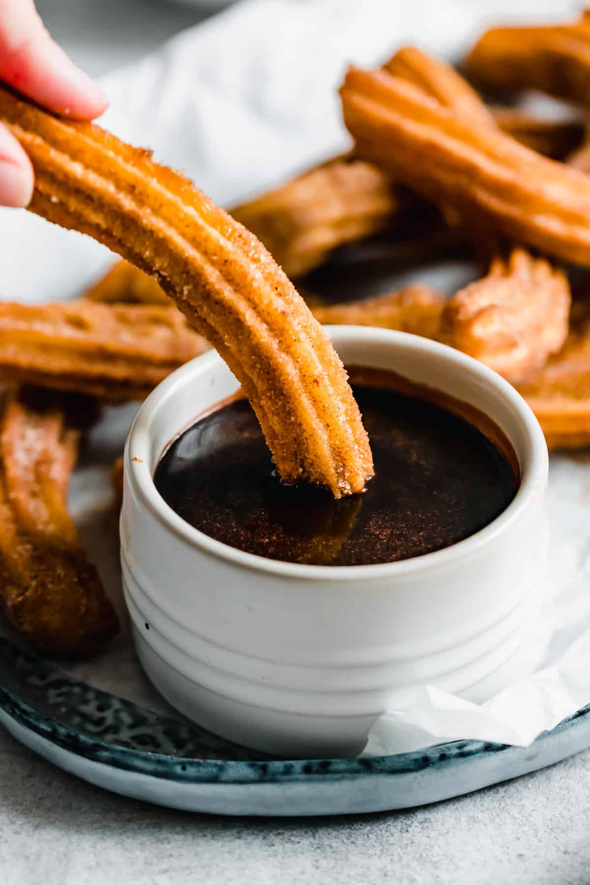 A Homemade Churro Being Dipped Into a Dish of Chocolate Sauce