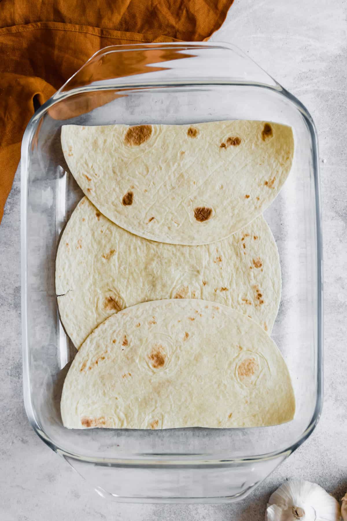 A Layer of Soft Corn Tortillas in a Glass Baking Dish