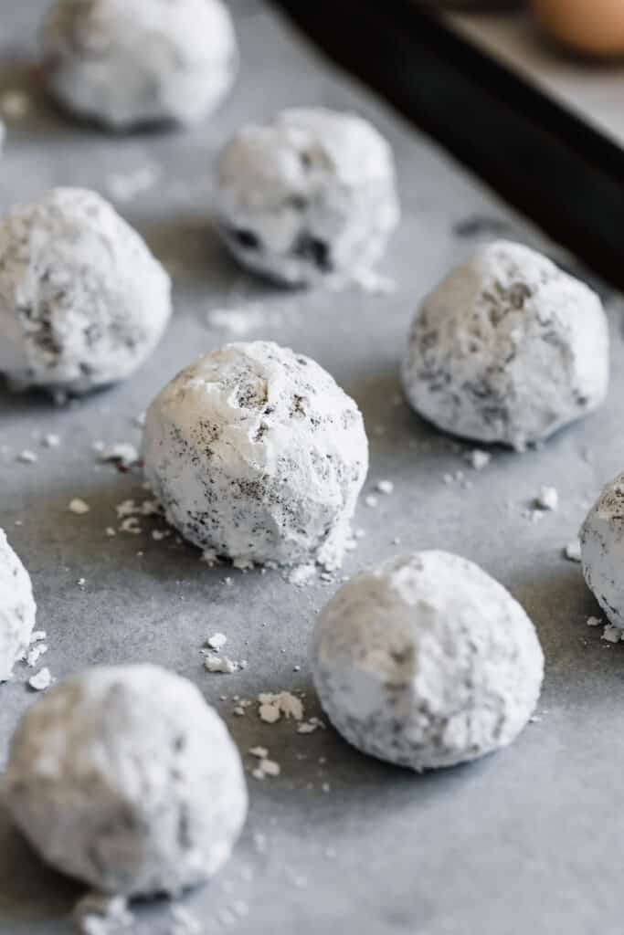A Parchment-Lined Baking Sheet with Powdered Sugar-Dusted Balls of Dough On it