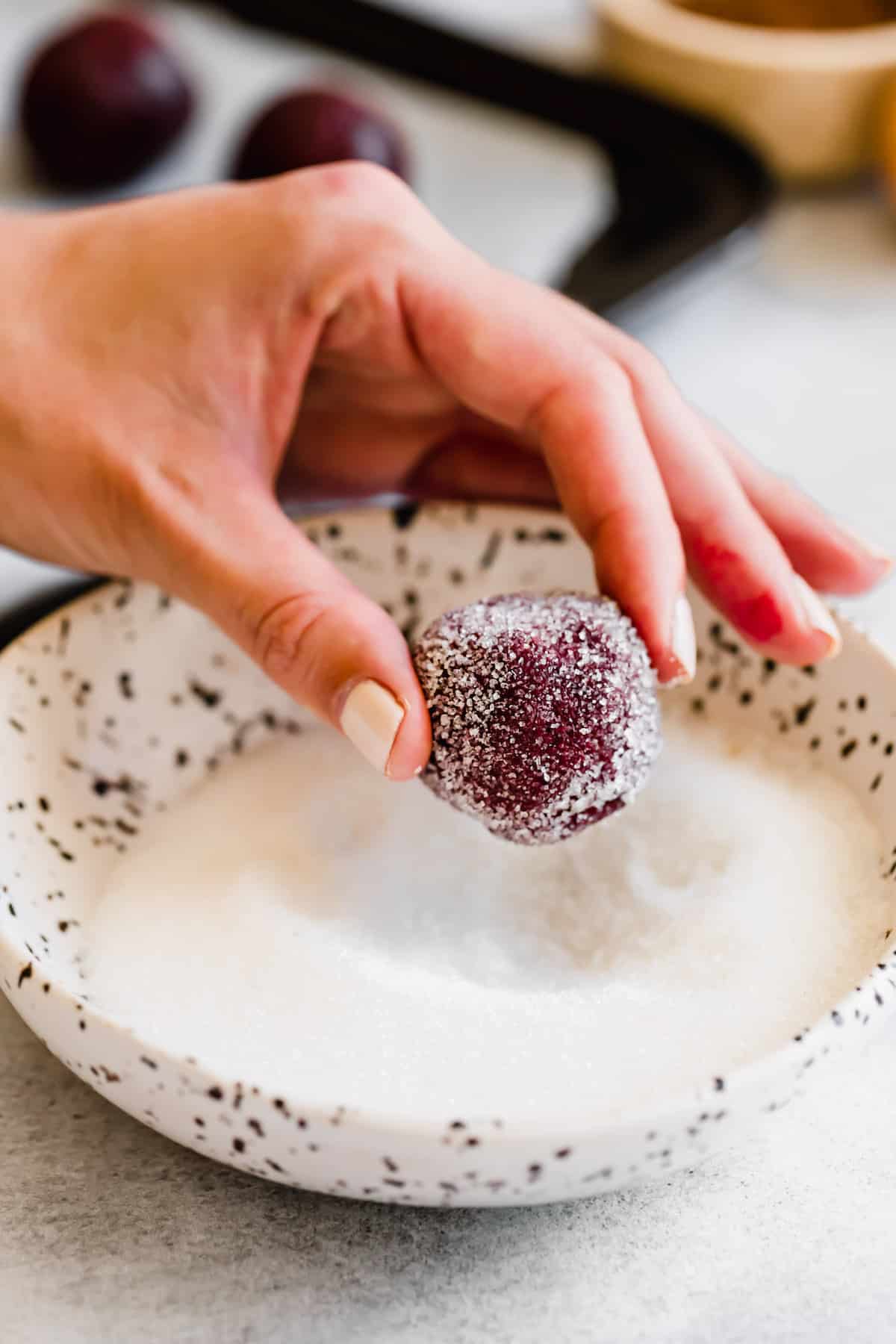 A Hand Holding a Sugar-Coated Ball of Red Velvet Cookie Dough