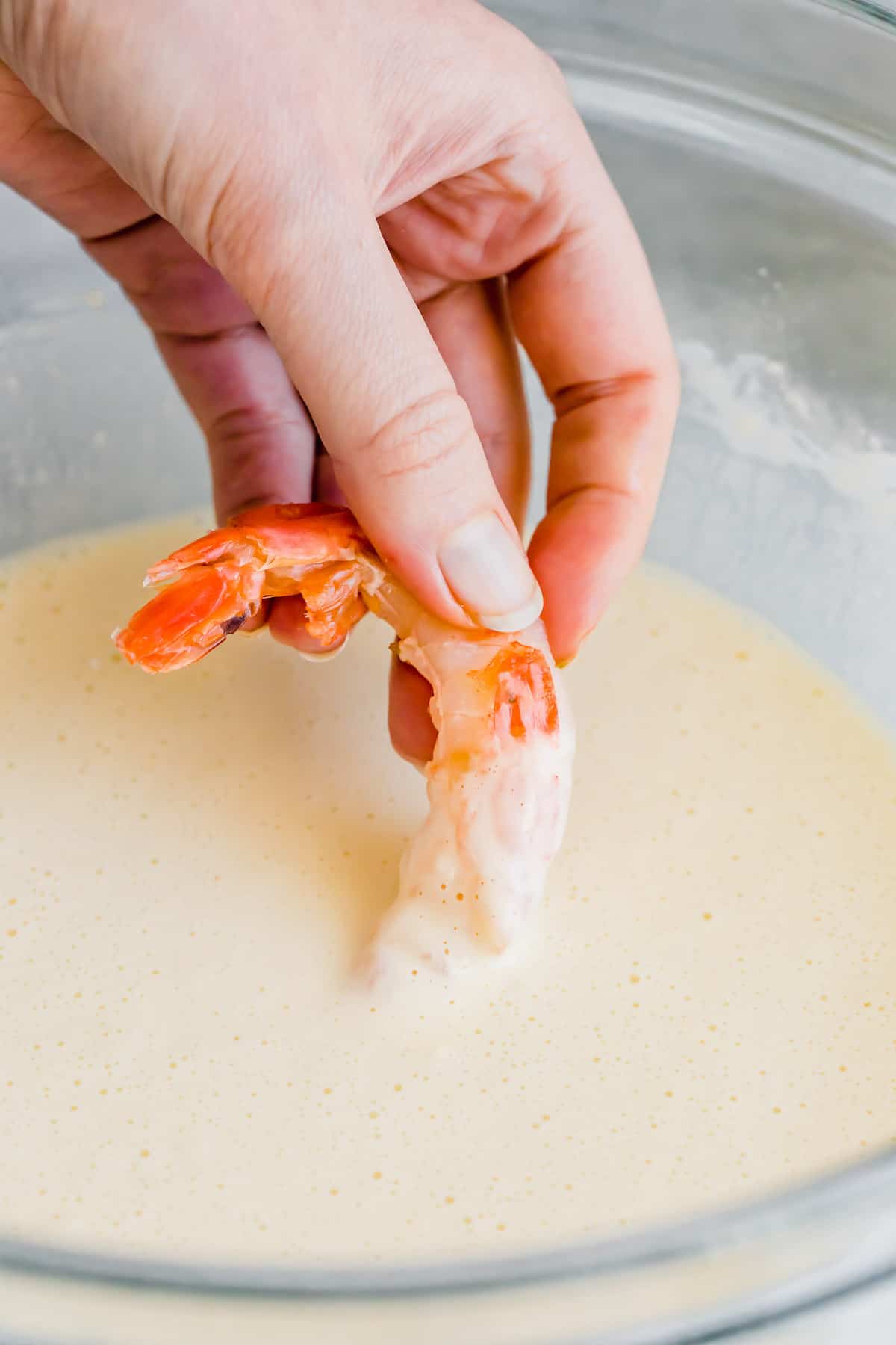 A Raw Shrimp Being Dunked Into a Bowl of Tempura Batter