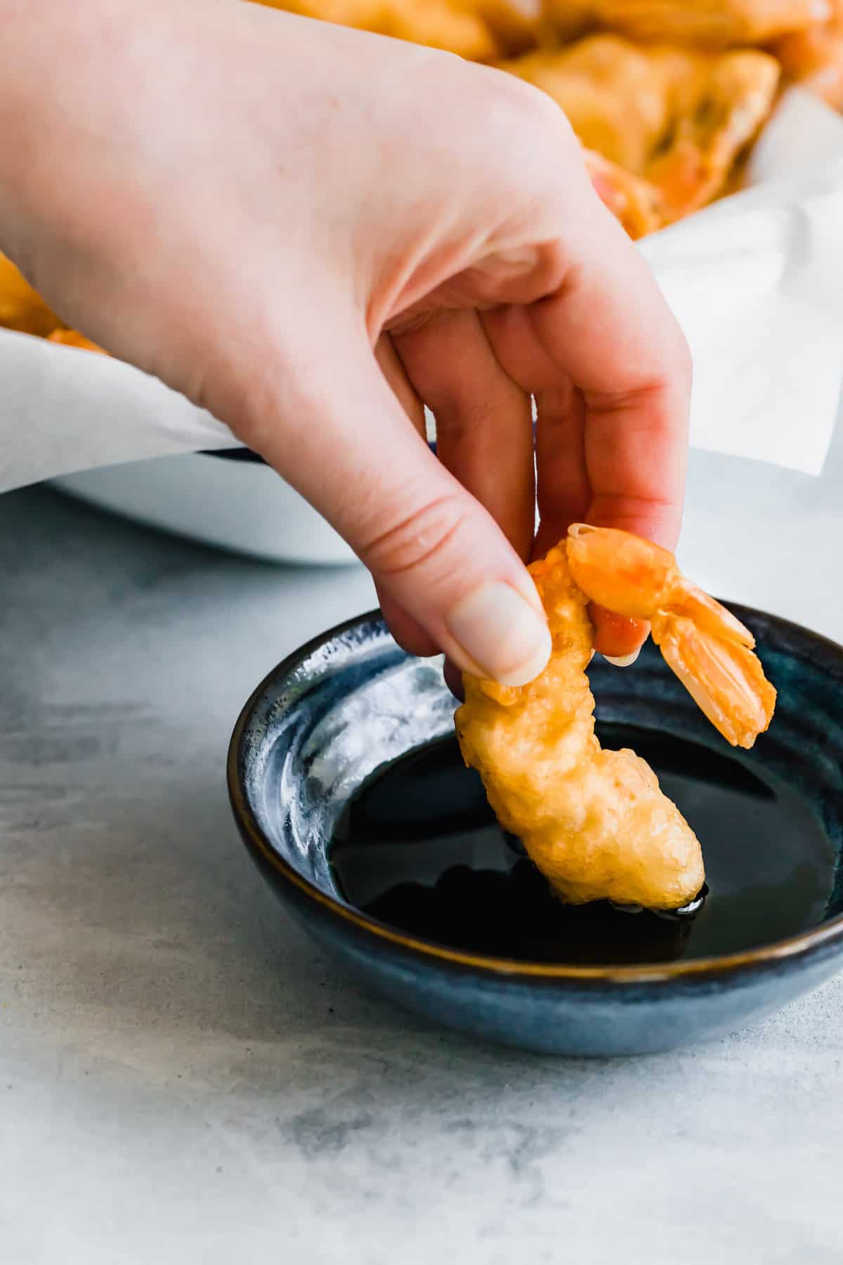 A Piece of Shrimp Tempura Being Dipped Into a Dish of Soy Sauce