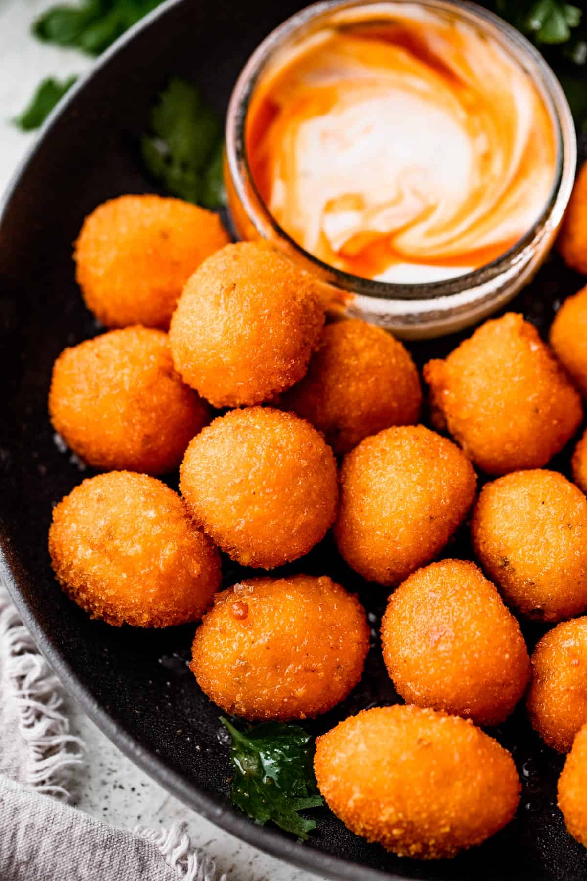 up close shot of air fryer cooked jalapeno popper balls and a dipping sauce placed next to them.