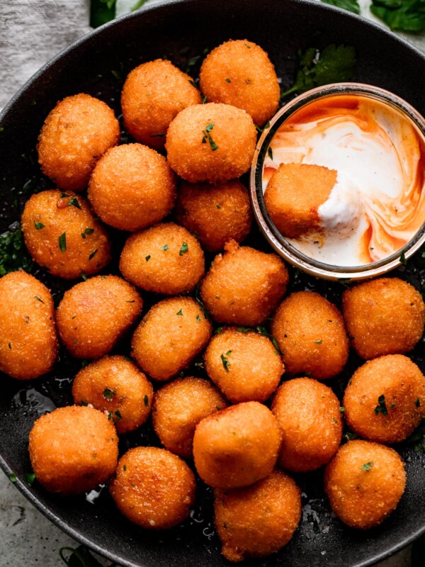 overhead shot of Jalapeno Popper Balls in a black bowl with a Dipping Sauce