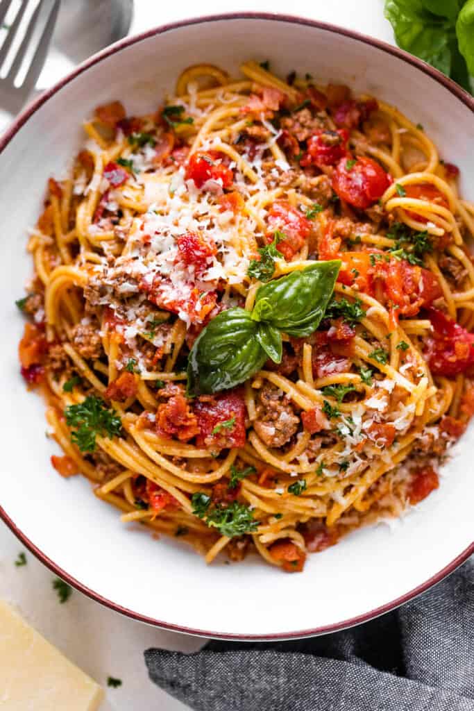 overhead shot of a spaghetti bowl topped with tomatoes and basil