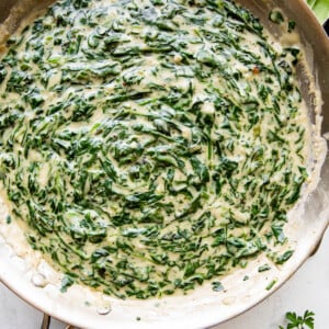 overhead picture of creamed spinach cooking in a large skillet.