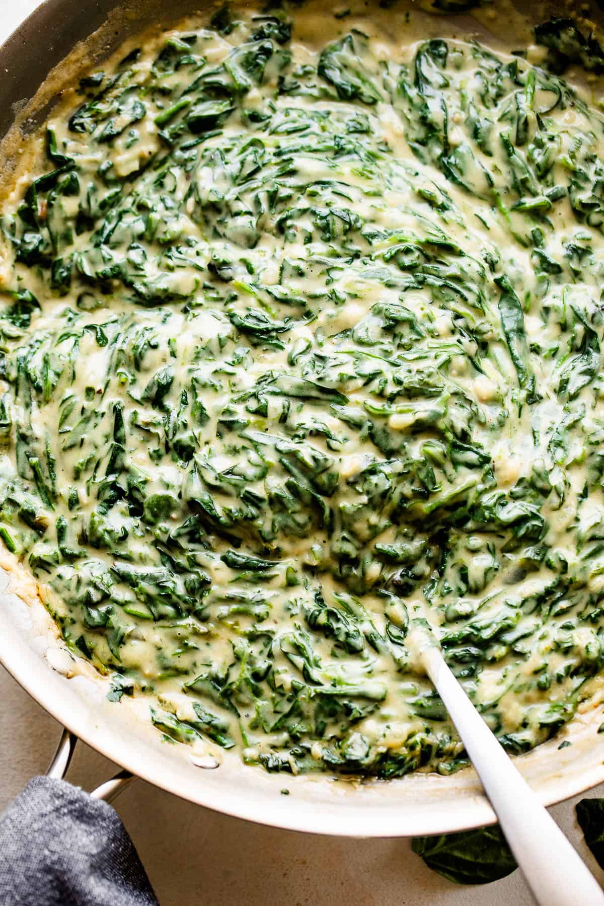 overhead picture of creamed spinach cooking in a large skillet