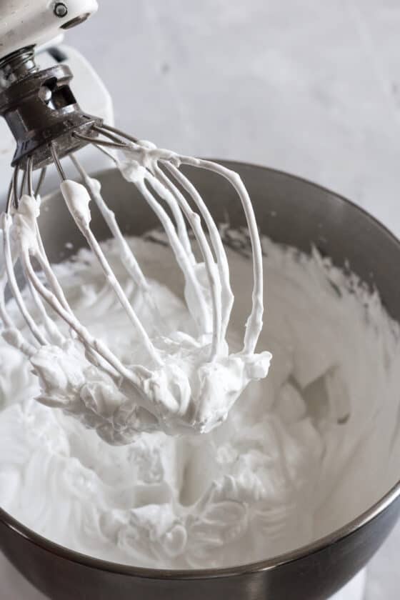 The whisk of a stand mixer with whipped meringue