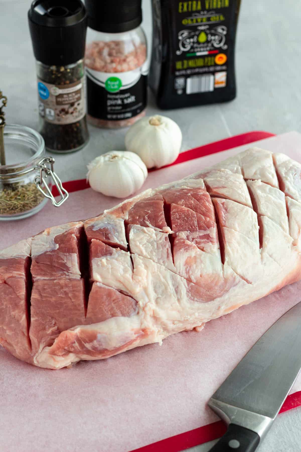 This easy pork loin roast is juicy, tender, and seasoned with garlic and herbs. Roasted with potatoes, carrots, and celery, it’s a complete one-pan dinner. The Criss-Cross Slicing Method Exhibited on a Roast Over a Red Cutting Board