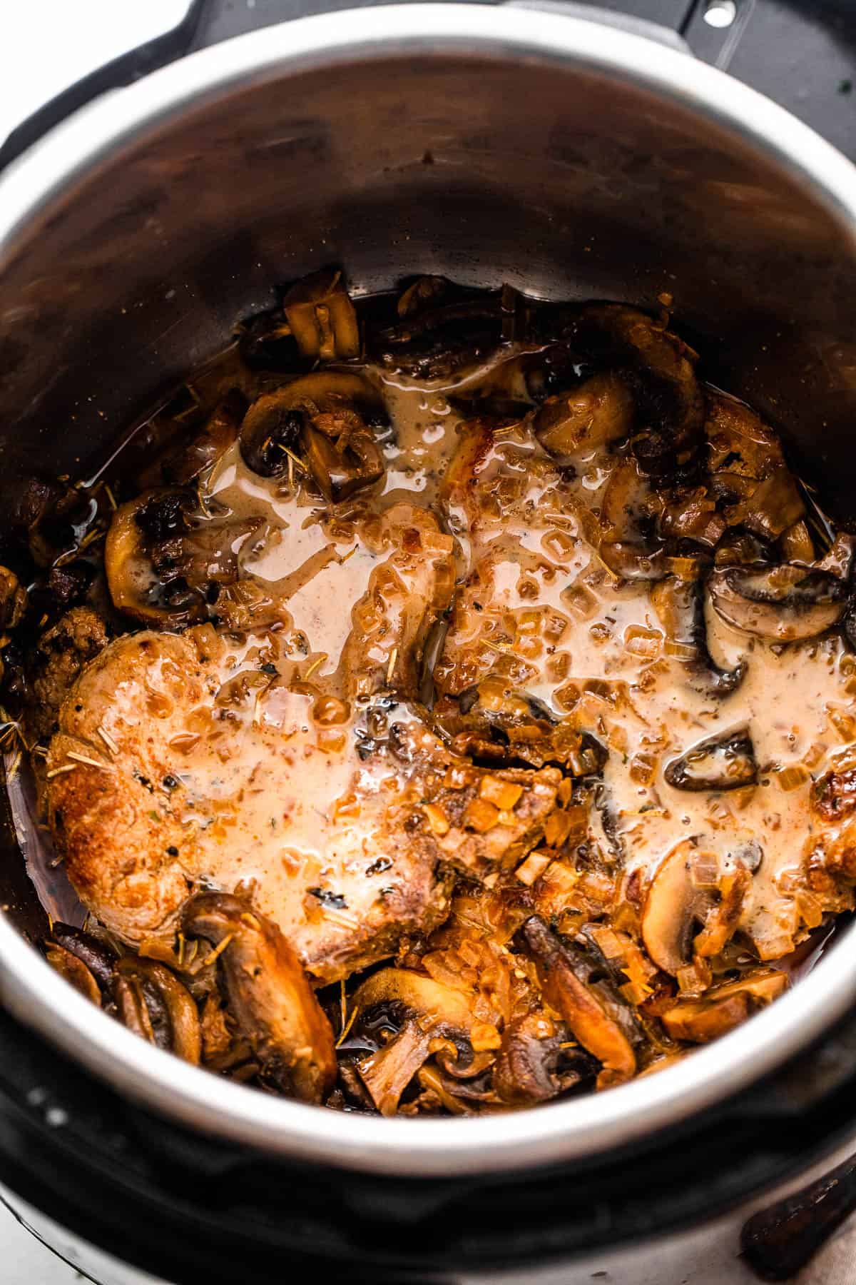 overhead shot of two pork chops in the instant pot topped with mushroom gravy sauce