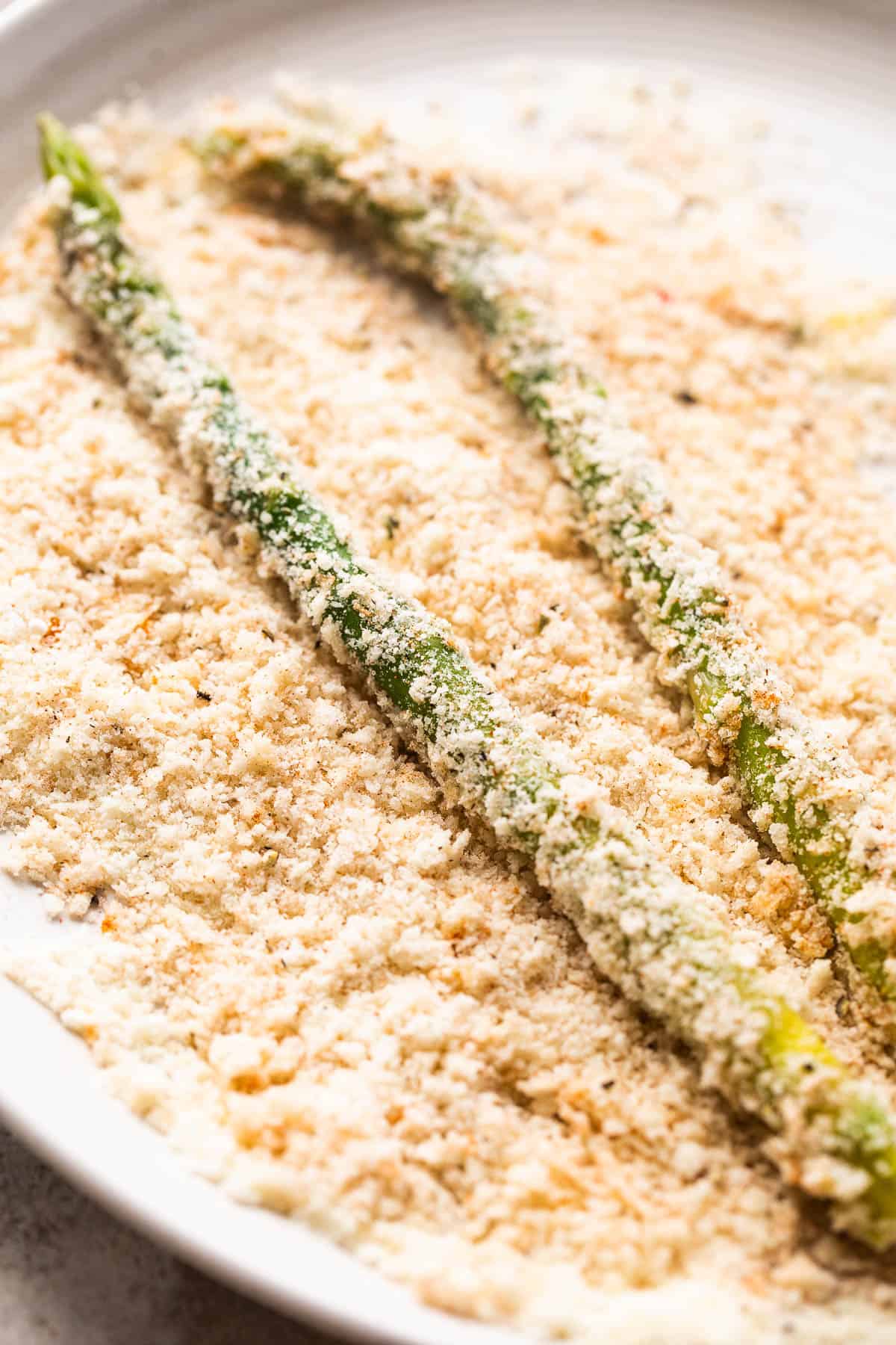 rolling fresh asparagus spears in panko bread crumb mixture