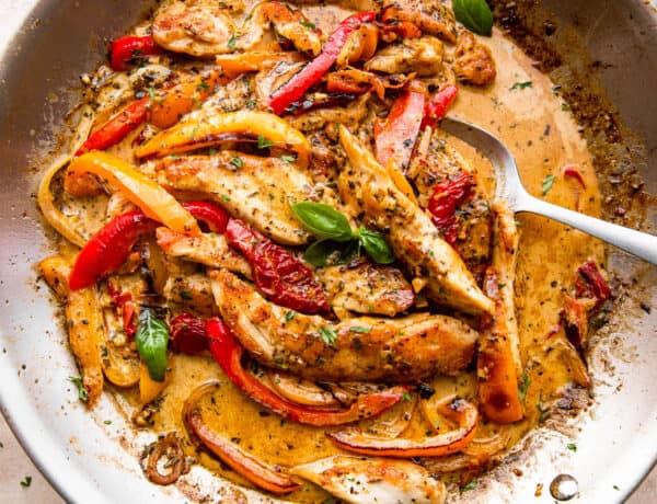overhead shot of a skillet with creamy pesto chicken strips, peppers, and cream sauce