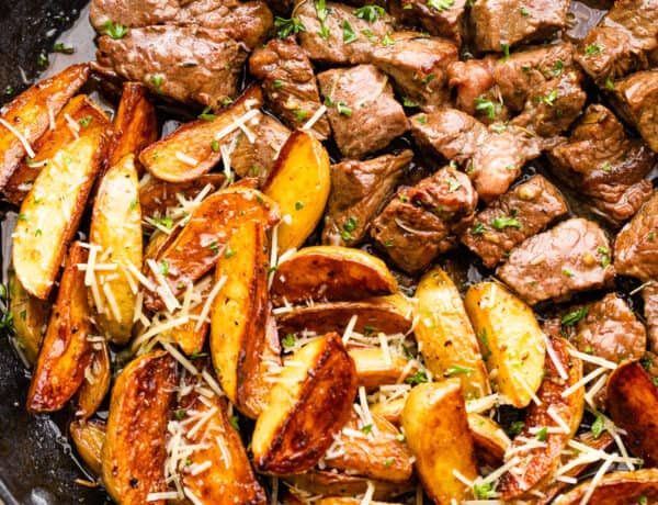 cubed steak and quartered potatoes cooking in a skillet
