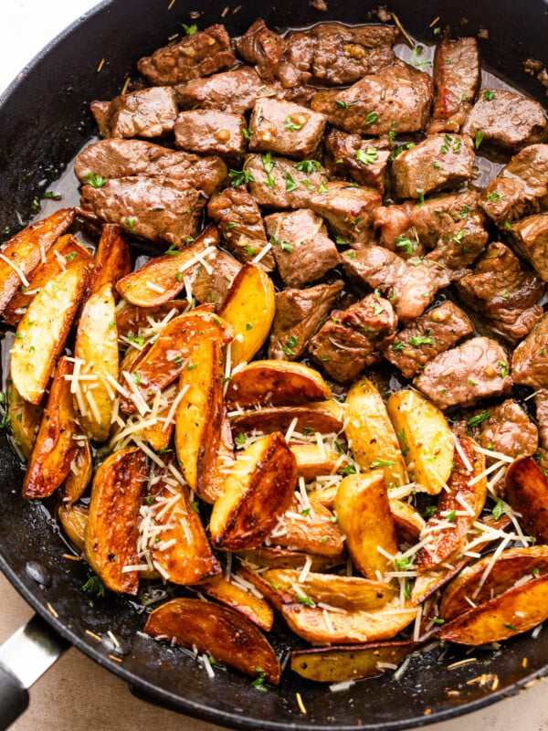 cubed steak and quartered potatoes cooking in a skillet