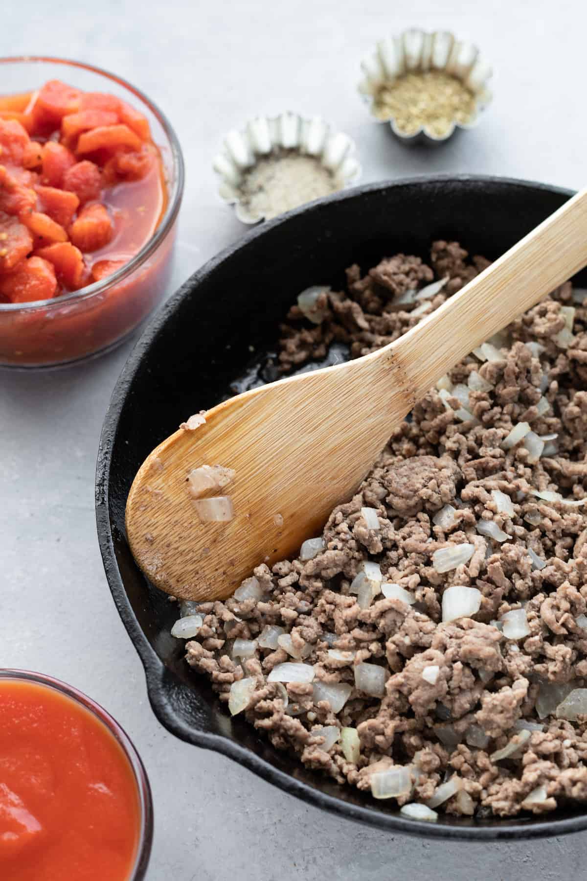 Browned Ground Beef and Chopped Onions Being Stirred by a Wooden Spoon