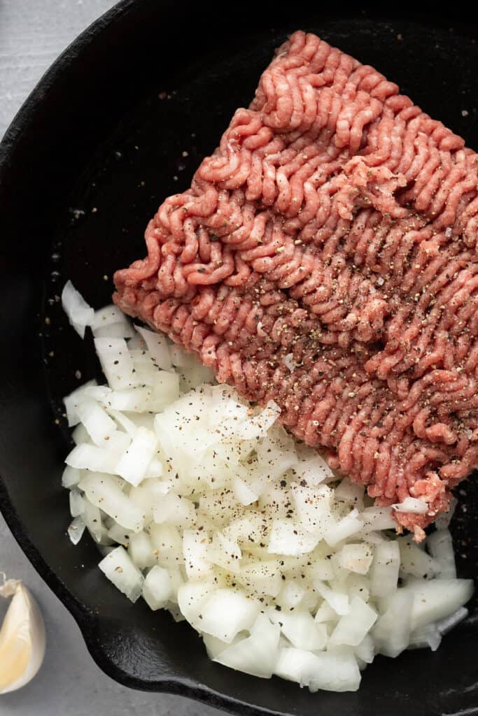 A Pound of Ground Beef and Chopped Onions in a Skillet with Seasonings